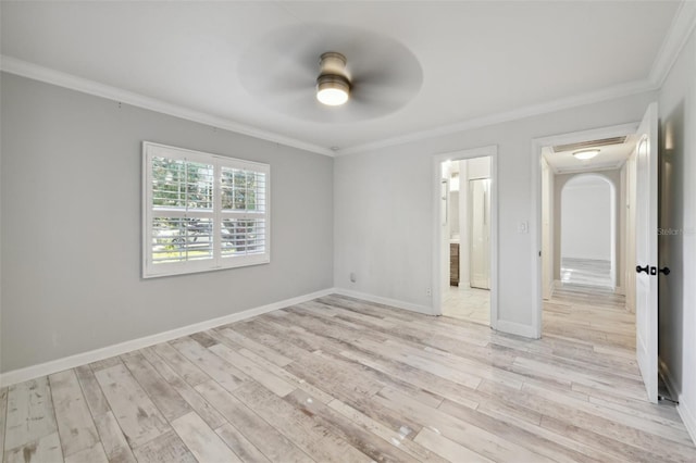 spare room featuring arched walkways, ornamental molding, light wood-style floors, ceiling fan, and baseboards