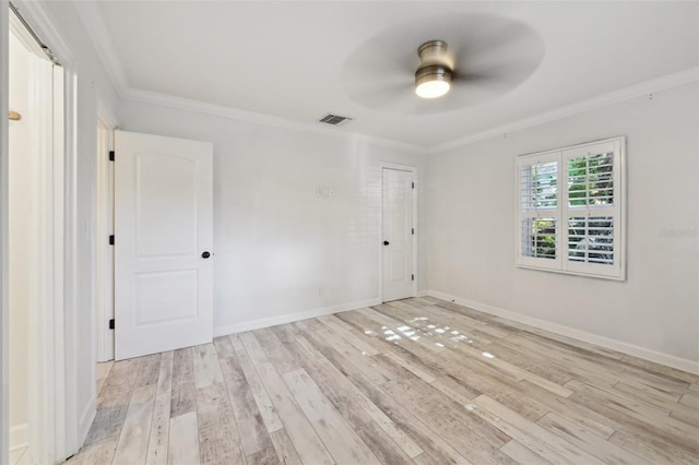 spare room with baseboards, light wood finished floors, visible vents, and crown molding