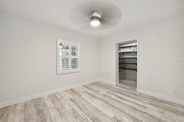 empty room featuring baseboards, a ceiling fan, and light wood-style floors