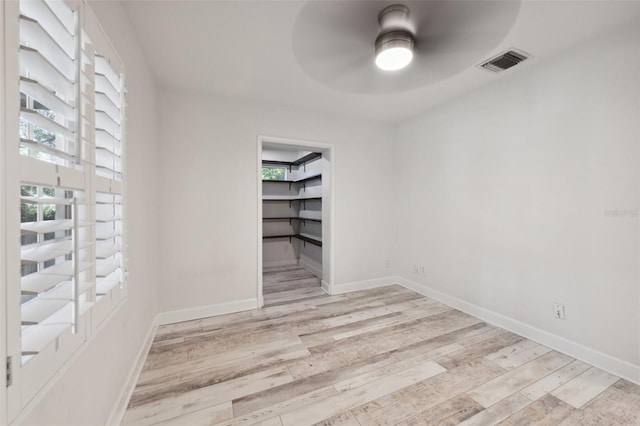 unfurnished room featuring a ceiling fan, baseboards, visible vents, and wood finished floors