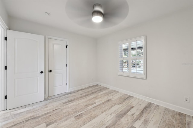 unfurnished room with a ceiling fan, light wood-style flooring, and baseboards