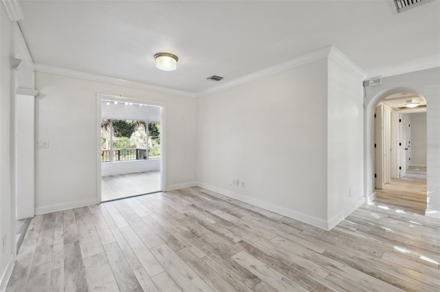 spare room featuring light wood finished floors, visible vents, arched walkways, and crown molding