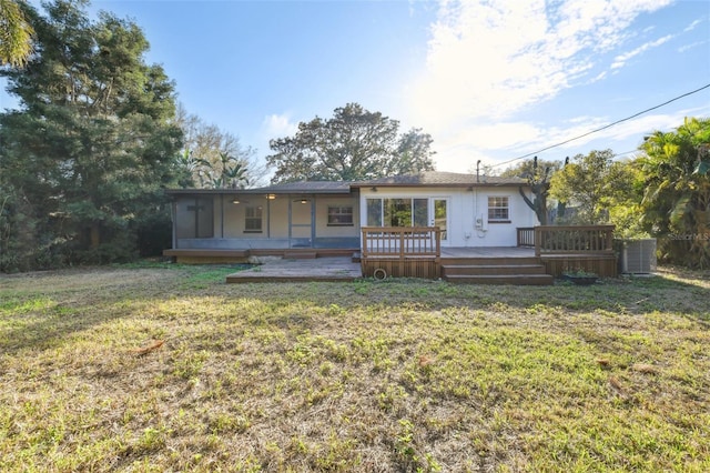 back of property featuring a deck, a lawn, and a sunroom