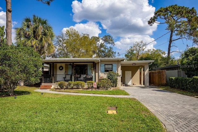 view of front of property with decorative driveway, covered porch, a front lawn, and stucco siding