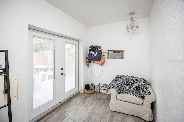 doorway to outside with an AC wall unit, a textured wall, wood finished floors, and french doors