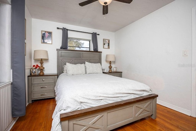 bedroom featuring a ceiling fan, baseboards, and wood finished floors