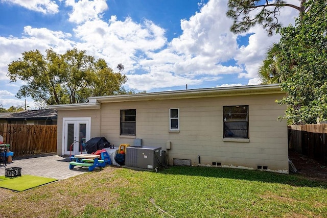 back of property with a yard, french doors, a patio area, and a fenced backyard