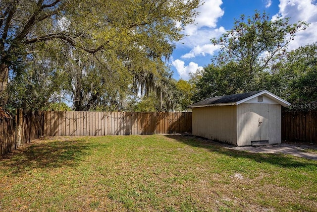 view of yard featuring an outbuilding, a fenced backyard, and a shed