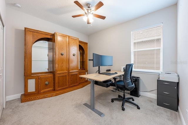 office space featuring light colored carpet, ceiling fan, a textured ceiling, and baseboards