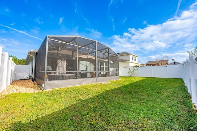 back of property with glass enclosure, a fenced backyard, and a lawn