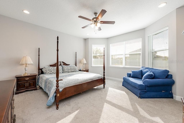 bedroom with light carpet, multiple windows, a textured ceiling, and baseboards