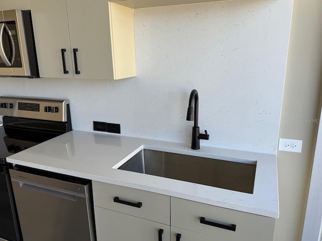 kitchen with stainless steel appliances, a sink, and light stone countertops