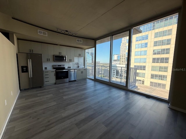 kitchen with dark wood-type flooring, visible vents, appliances with stainless steel finishes, a wall of windows, and rail lighting