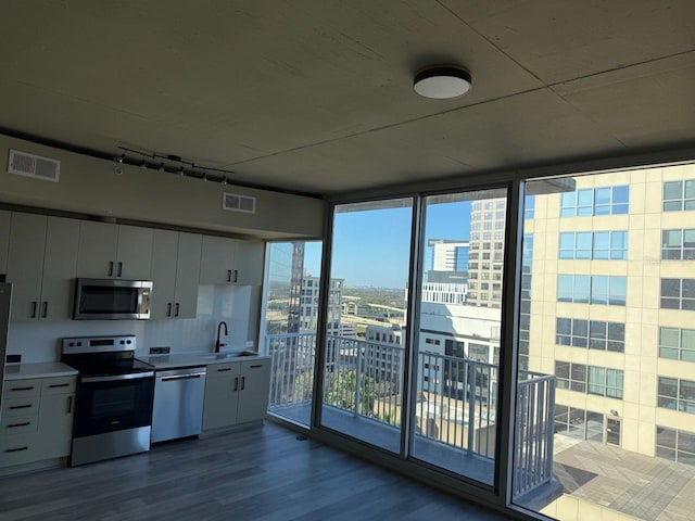 kitchen with dark wood-style floors, stainless steel appliances, visible vents, white cabinetry, and a sink