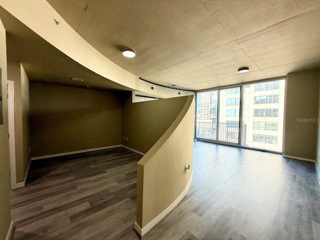 hall with dark wood-style floors, a wall of windows, and baseboards