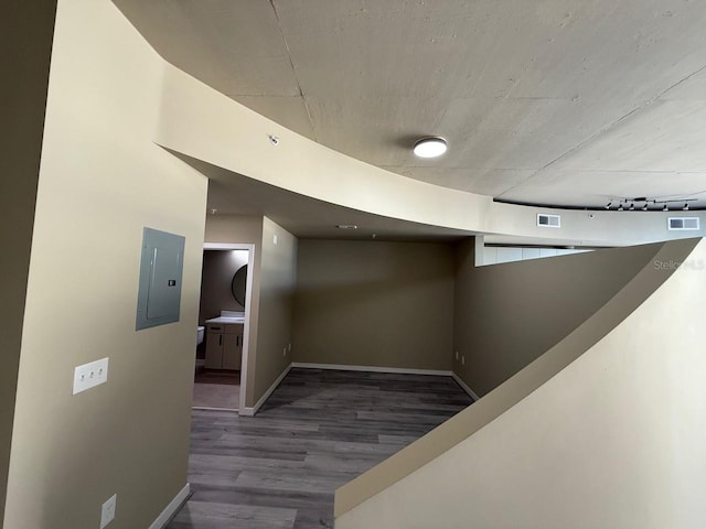 hallway featuring visible vents, wood finished floors, electric panel, and baseboards