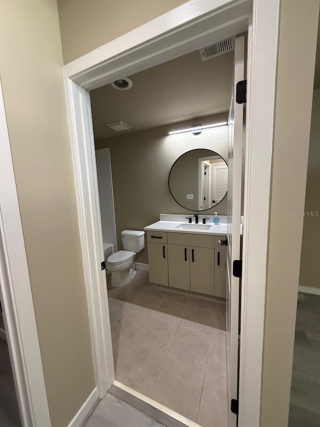 half bath with visible vents, toilet, vanity, baseboards, and tile patterned floors