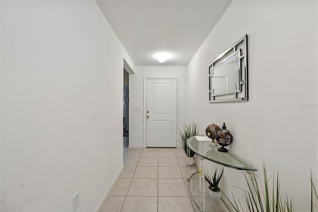 hall with baseboards and light tile patterned floors