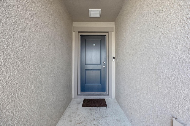 entrance to property with visible vents and stucco siding