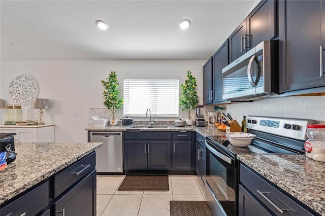 kitchen with light stone counters, light tile patterned floors, stainless steel appliances, recessed lighting, and a sink