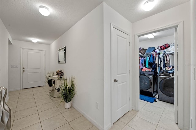 hallway featuring washing machine and dryer, a textured ceiling, and light tile patterned flooring