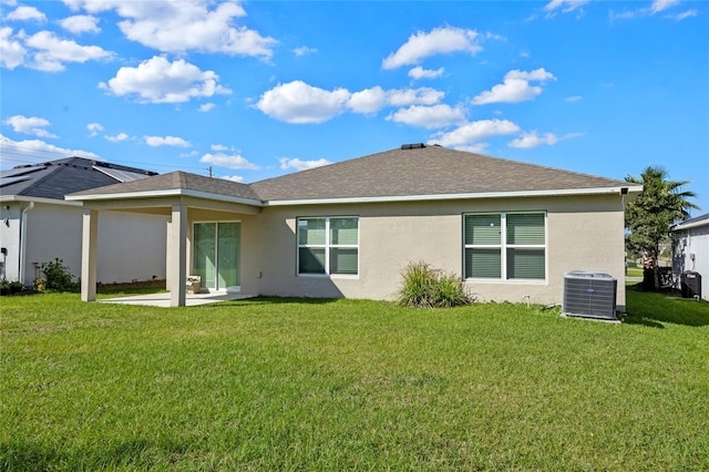 rear view of property featuring a lawn, roof with shingles, cooling unit, a patio area, and stucco siding