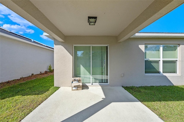 doorway to property with a lawn, a patio area, and stucco siding