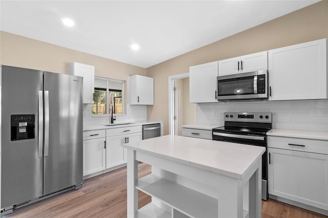 kitchen with appliances with stainless steel finishes, white cabinetry, a sink, and decorative backsplash