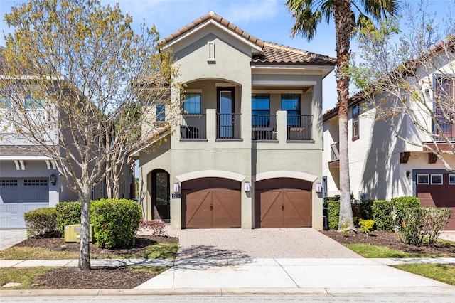 mediterranean / spanish-style home featuring stucco siding, decorative driveway, an attached garage, and a tile roof