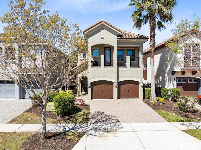 mediterranean / spanish-style house with a tiled roof, decorative driveway, an attached garage, and stucco siding