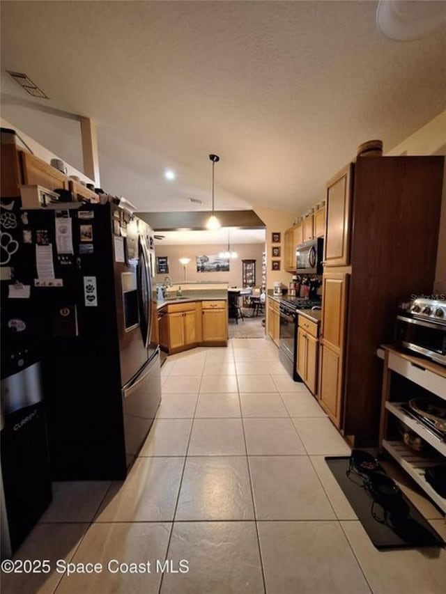 kitchen featuring light tile patterned floors, stainless steel appliances, vaulted ceiling, and visible vents