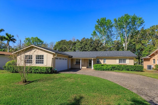 ranch-style house featuring a garage, a front yard, decorative driveway, and central air condition unit