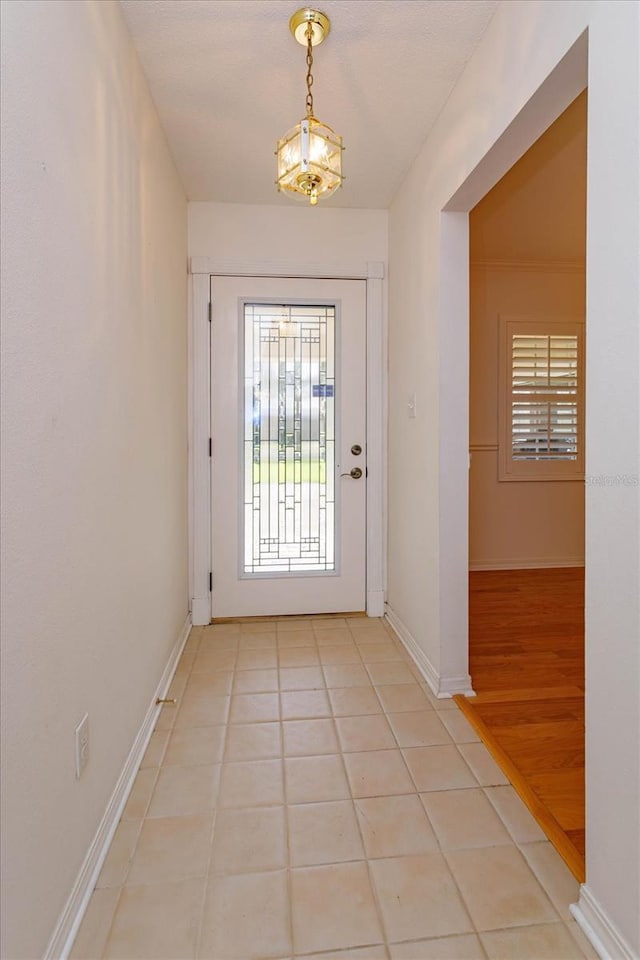 doorway with baseboards and light tile patterned floors