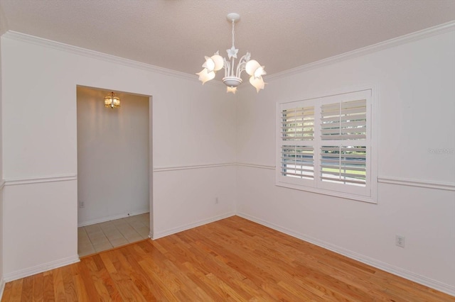 spare room featuring crown molding, a textured ceiling, wood finished floors, and a notable chandelier