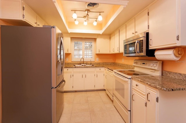 kitchen featuring a tray ceiling, visible vents, appliances with stainless steel finishes, light tile patterned flooring, and a sink