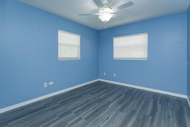 unfurnished room with a ceiling fan, dark wood finished floors, and baseboards