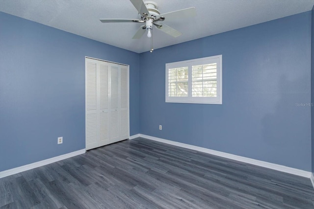 unfurnished bedroom with ceiling fan, baseboards, dark wood-type flooring, and a closet