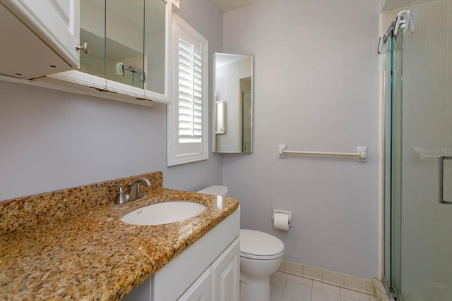 bathroom featuring toilet, a stall shower, vanity, tile patterned flooring, and baseboards