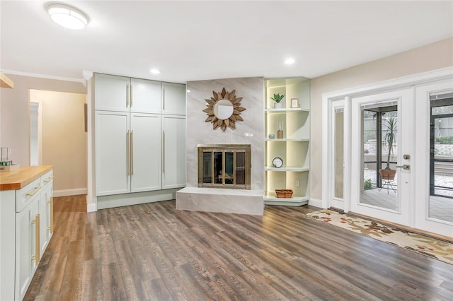 unfurnished living room featuring a large fireplace, baseboards, dark wood-type flooring, french doors, and recessed lighting