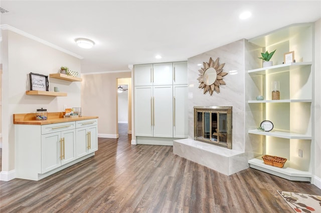 unfurnished living room featuring recessed lighting, wood finished floors, a high end fireplace, baseboards, and crown molding