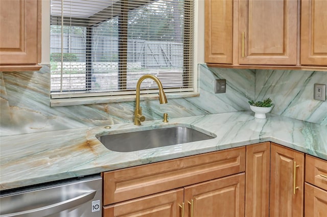 kitchen with light stone counters, dishwasher, backsplash, and a sink