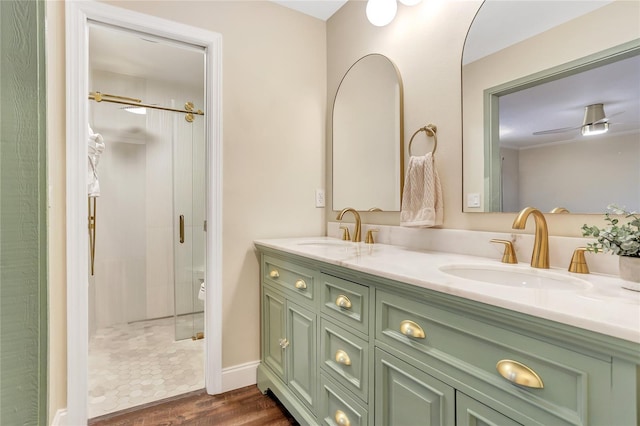 full bathroom with double vanity, a stall shower, a sink, and wood finished floors