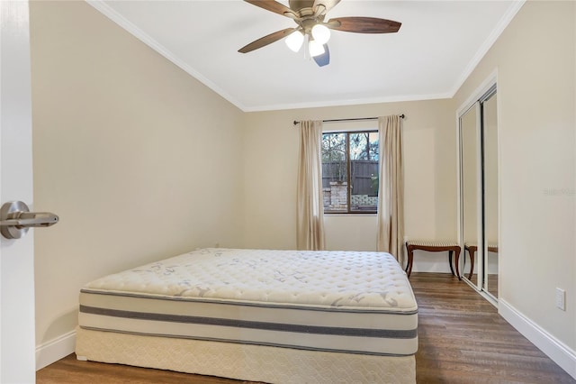 bedroom with baseboards, a ceiling fan, ornamental molding, dark wood-type flooring, and a closet