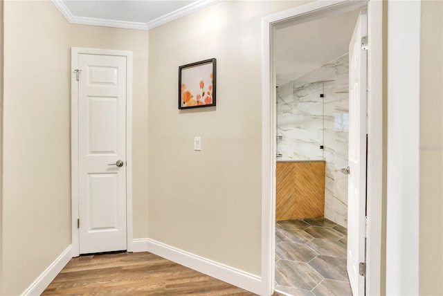 hallway with baseboards, wood finished floors, and crown molding