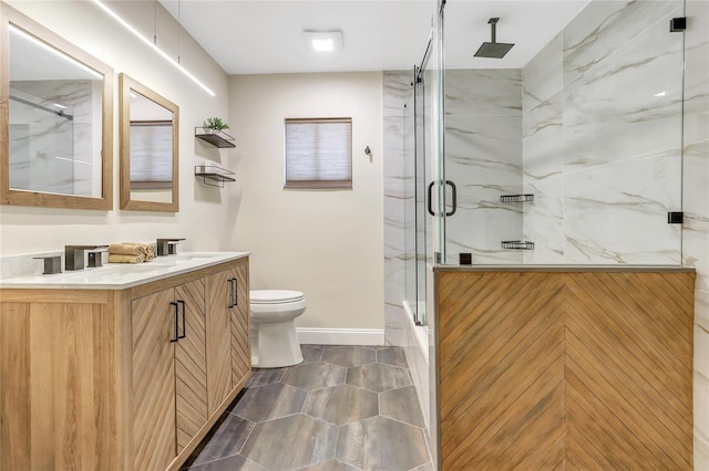 full bathroom with double vanity, a marble finish shower, toilet, and baseboards