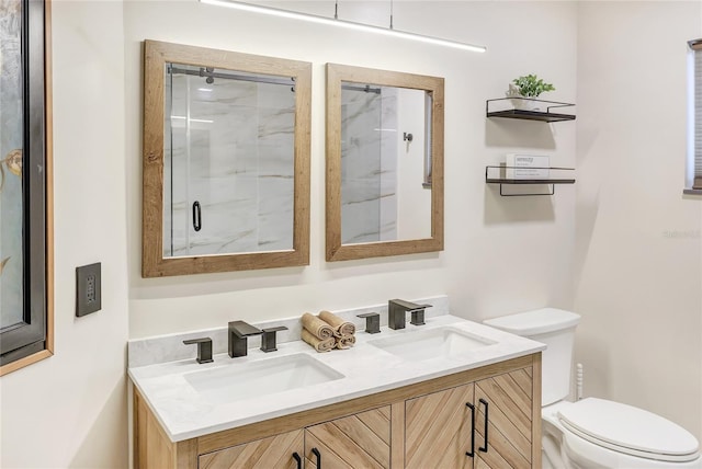 bathroom with toilet, a shower stall, double vanity, and a sink