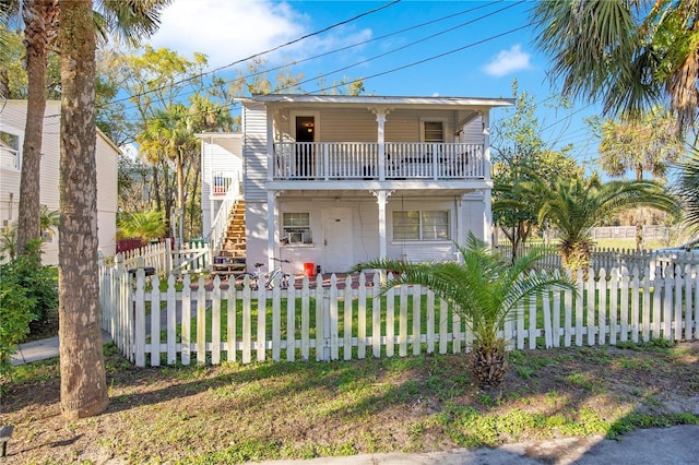 view of front facade with a balcony, a fenced front yard, and stairs