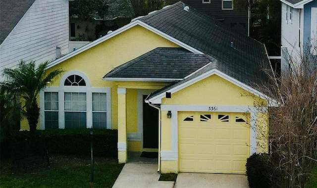 view of front of property with a garage, concrete driveway, roof with shingles, and stucco siding