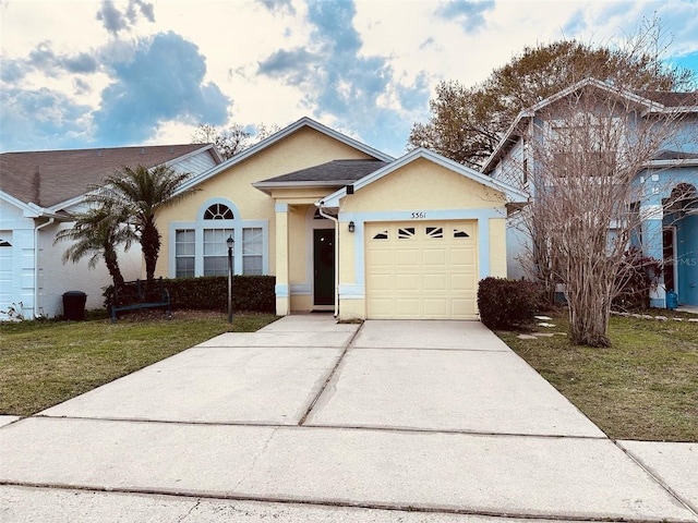 ranch-style home featuring driveway, a front yard, an attached garage, and stucco siding