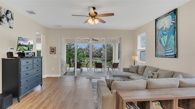 living room featuring plenty of natural light, visible vents, light wood-type flooring, and a ceiling fan